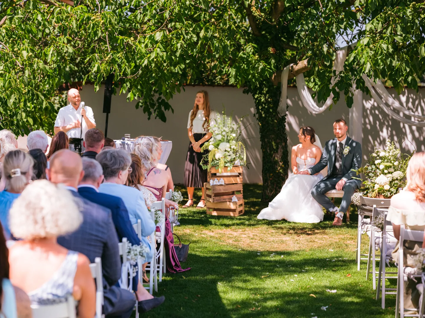 Brautpaar und Gäste während einer Zeremonie im Garten