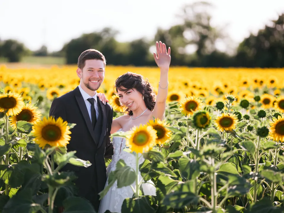Lachendes Brautpaar im Sonnenblumenfeld